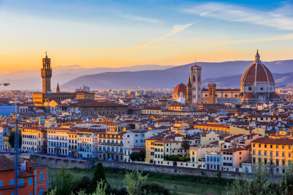 Iconic Florence skyline at sunset: Duomo, Campanile, and Palazzo Vecchio over the historic Tuscan city.