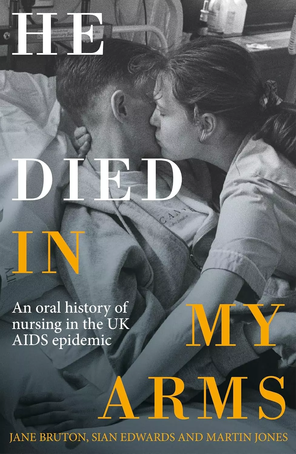 Book cover of He Died in My Arms, showing a nurse embracing and comforting a patient in a hospital bed.